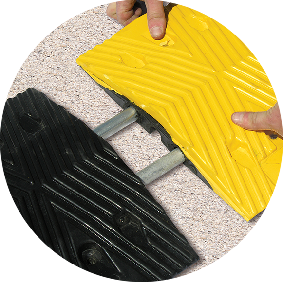 TreeTop Speed Bump with hands installing with steel rods on pavement” class=
